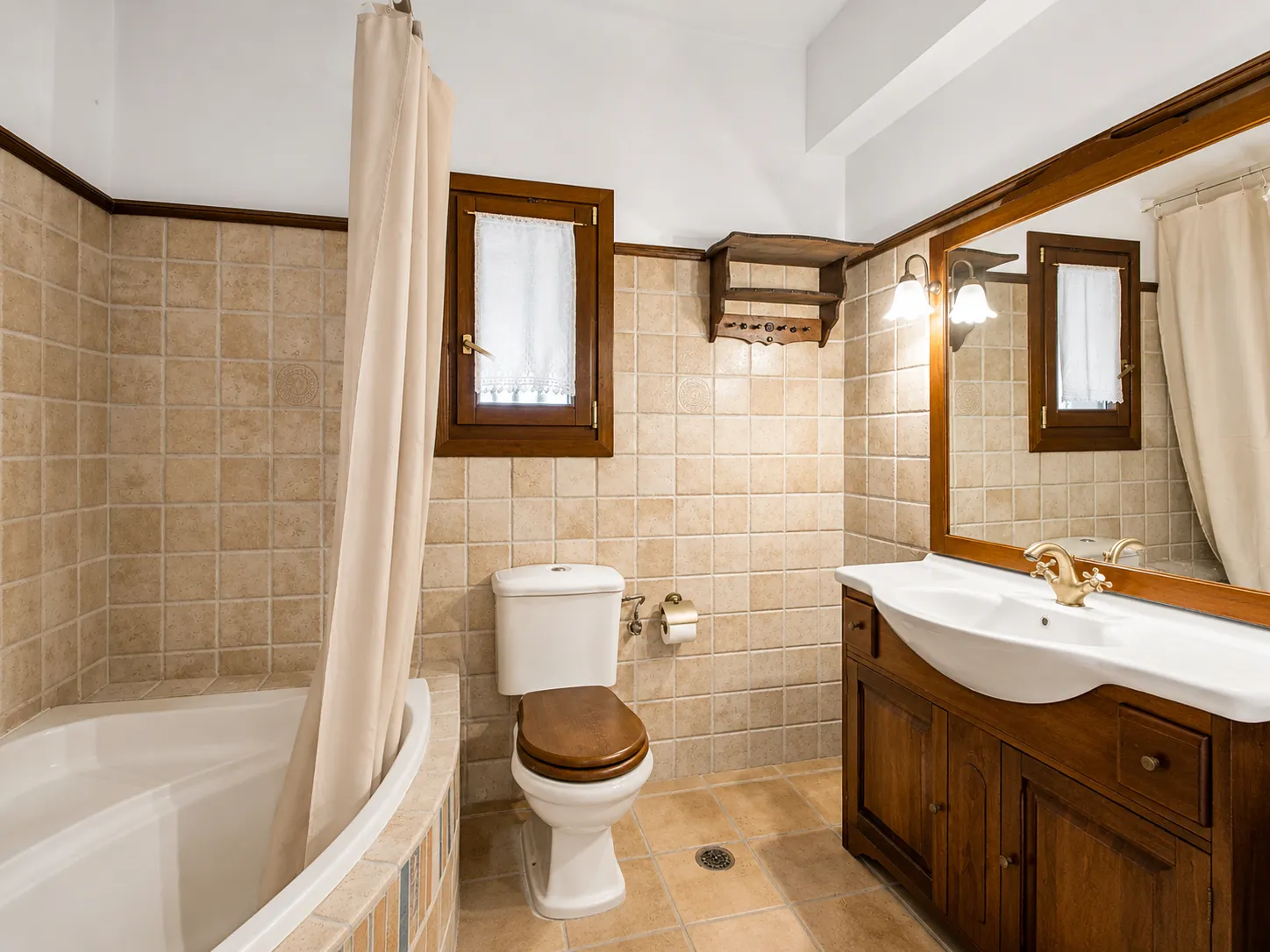 En-suite bathroom of the master bedroom with corner bathtub, wooden vanity and stone-tiled walls, Villa Viktoria Skiathos