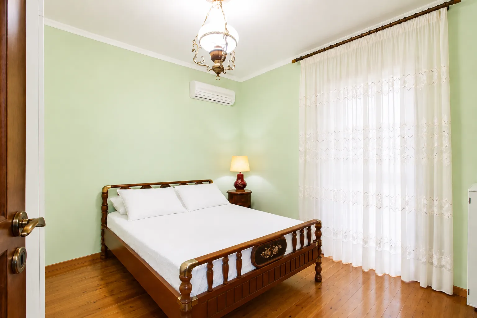 Double bedroom with green walls and carved wooden bed at Villa Viktoria, Skiathos