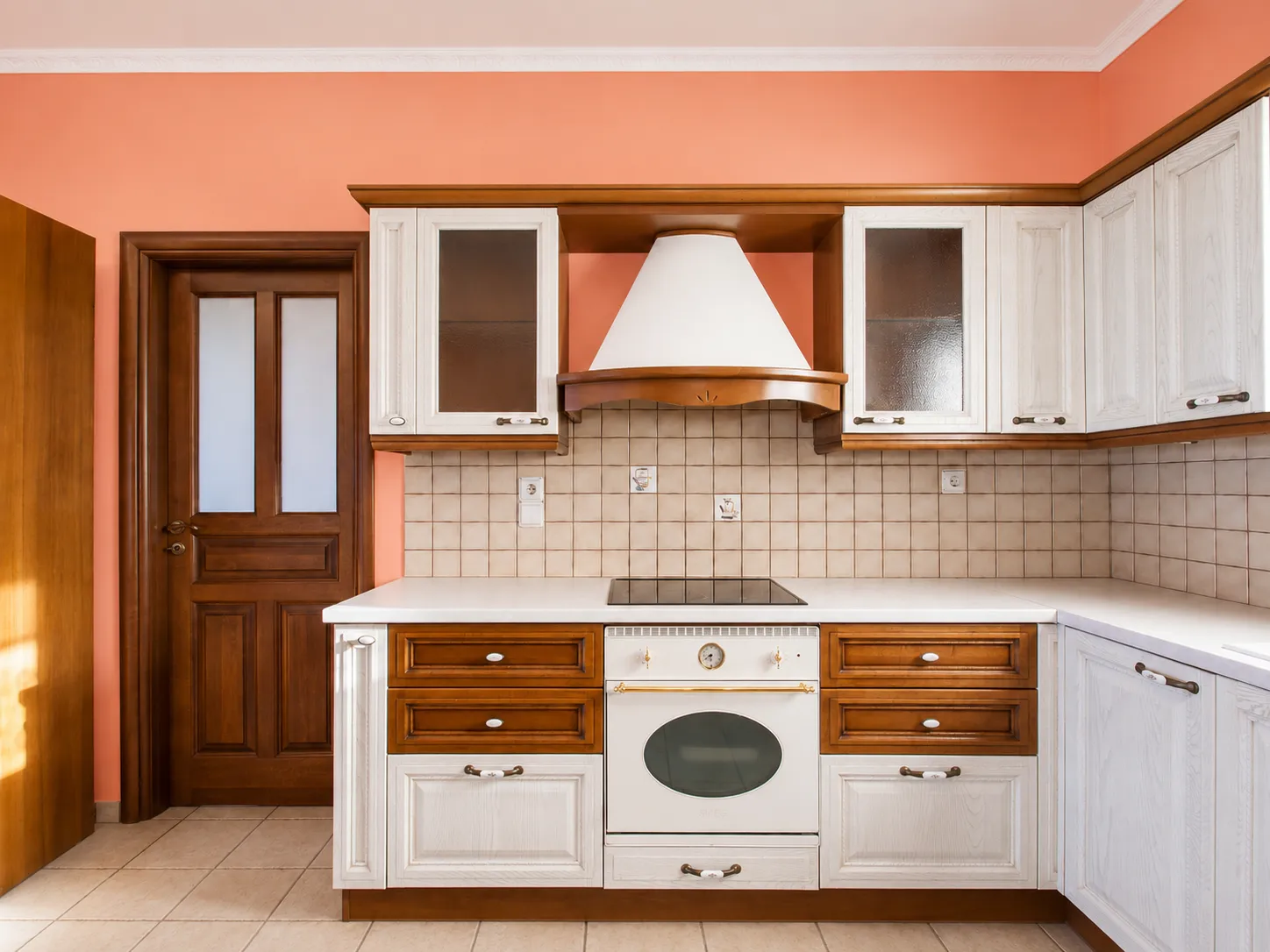 Kitchen with white-and-wood cabinetry, induction hob and chimney hood at Villa Viktoria