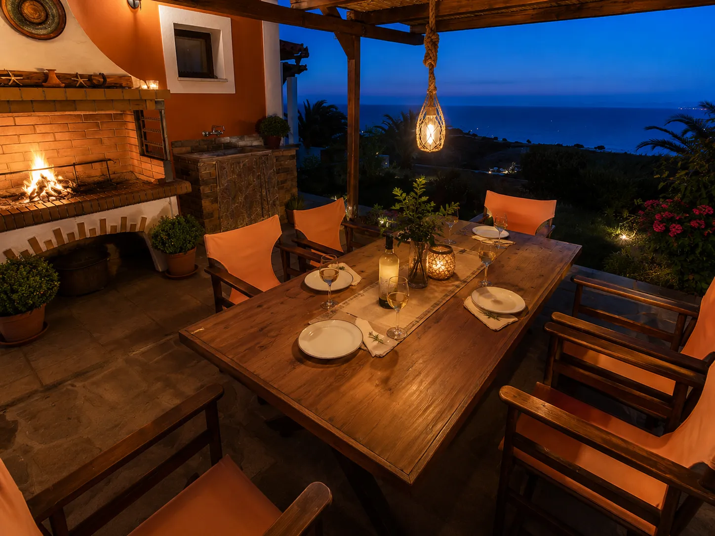 Outdoor table set at dusk with lit fireplace, candles and sea view, Villa Viktoria Skiathos